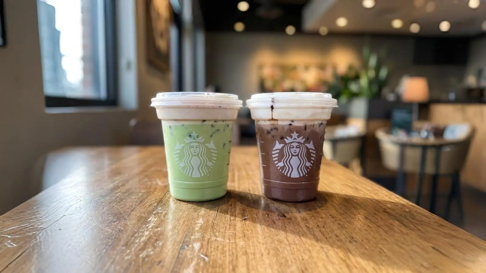 Starbucks Dubai Chocolate Matcha and Mocha iced drinks on a wooden cafe table